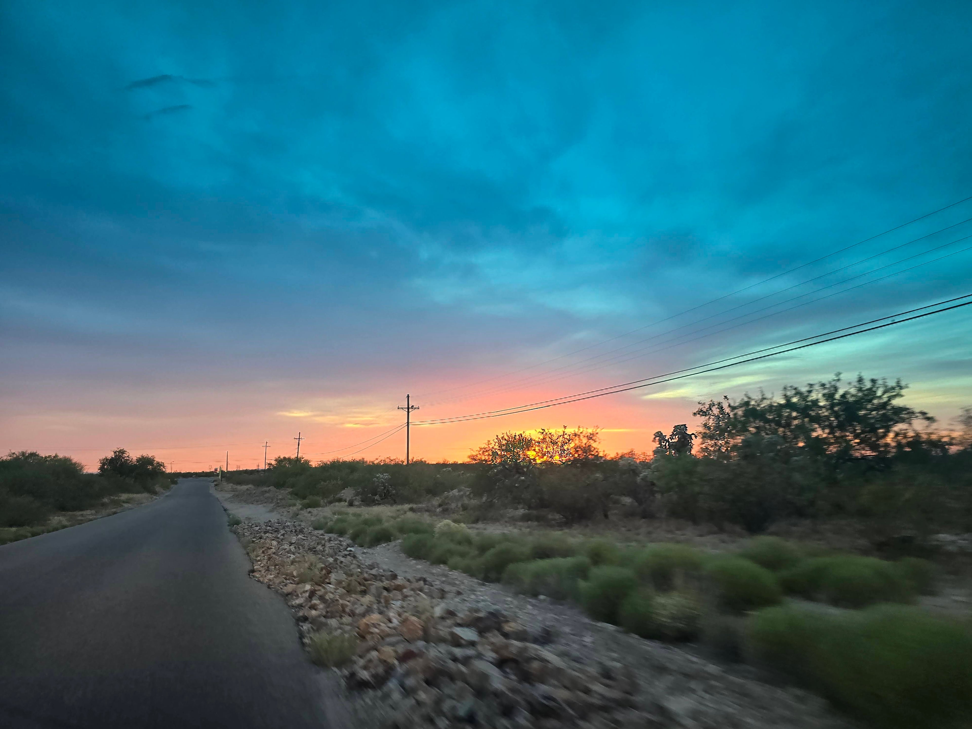 Desert road with sunset or sunrise sky and power lines.